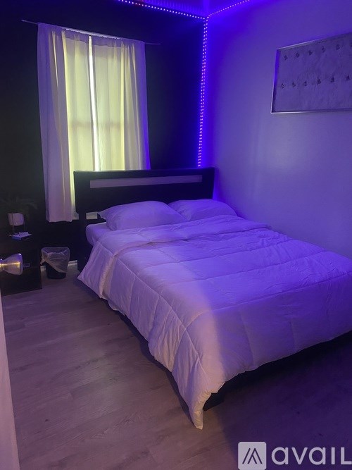 A bedroom with a bed, nightstand, and window with curtains.