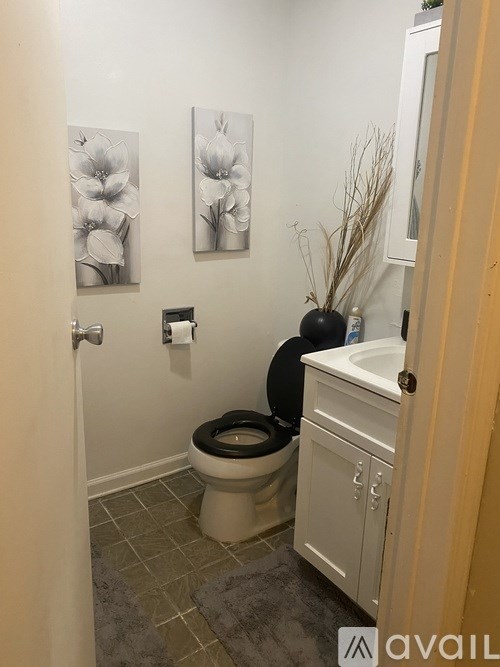 A bathroom with a toilet, sink, and two flower pictures on the wall.