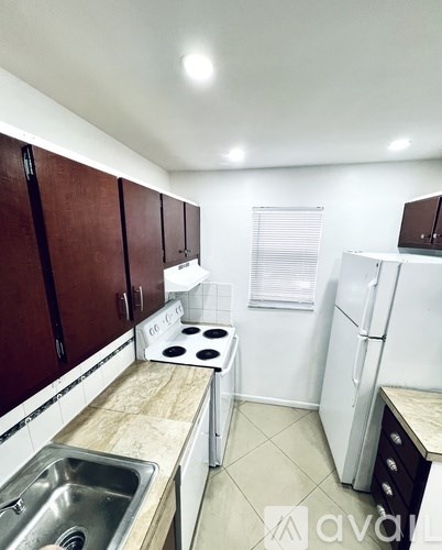 A kitchen with a stove, sink, and refrigerator.