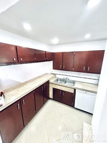 A kitchen with brown cabinets and a white dishwasher.