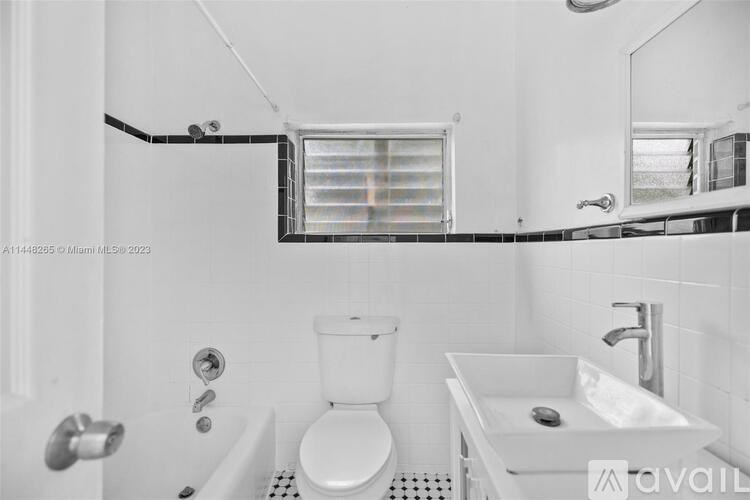 A white bathroom with a toilet, sink, and shower.