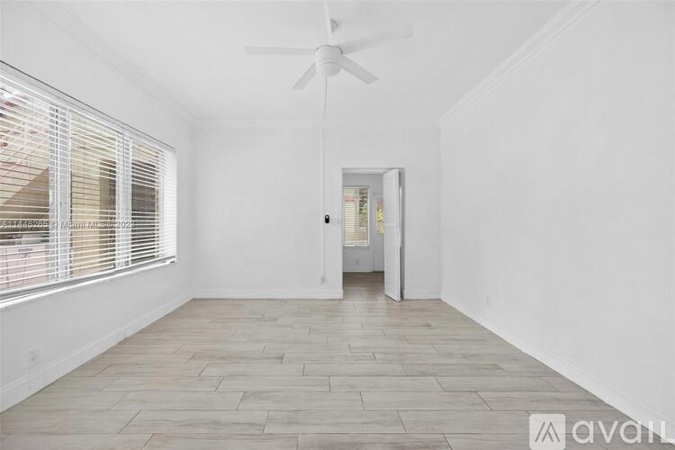 A room with a ceiling fan and a door leading to another room.