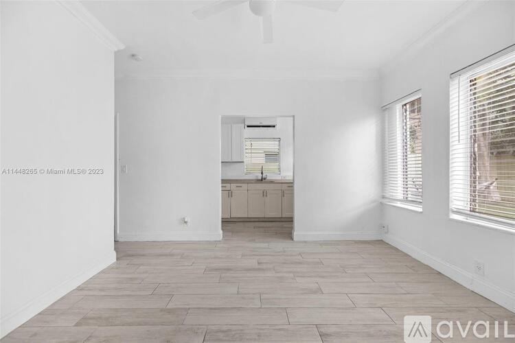 A spacious room with a wooden floor and a ceiling fan.