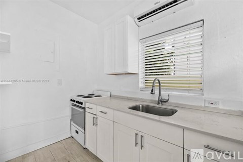 A kitchen with white cabinets and a stove top oven.
