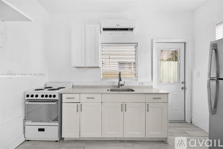 A kitchen with white cabinets and appliances is available for rent.