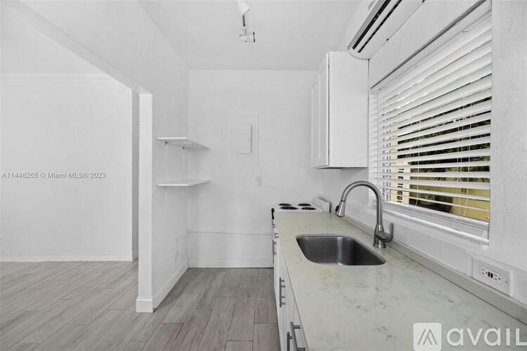 A kitchen with white cabinets and a marble countertop.