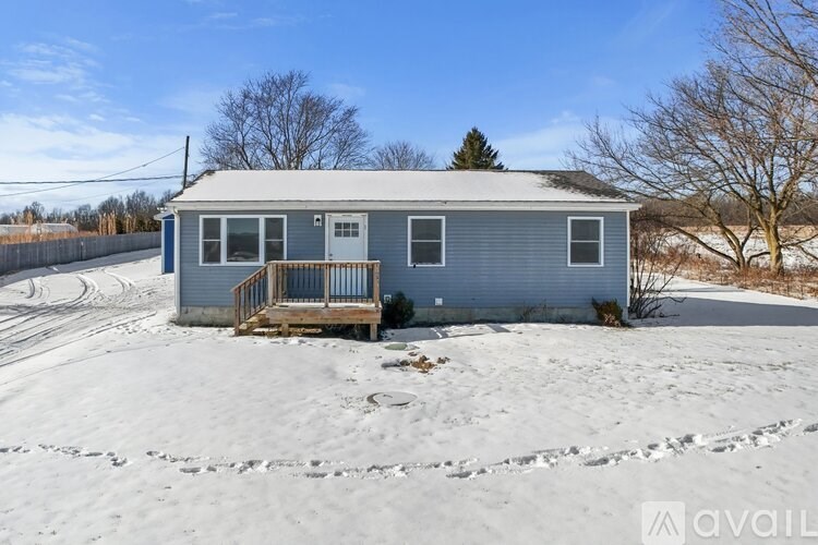 A small house with a porch is surrounded by snow.