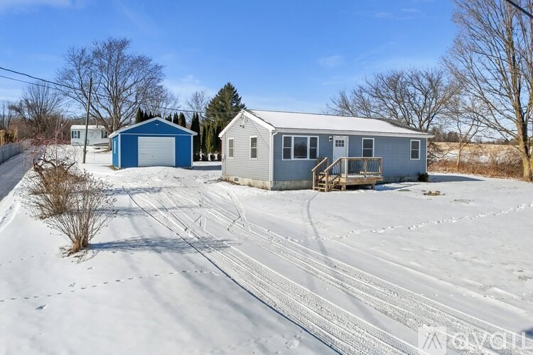 A house with a blue garage door is surrounded by snow.