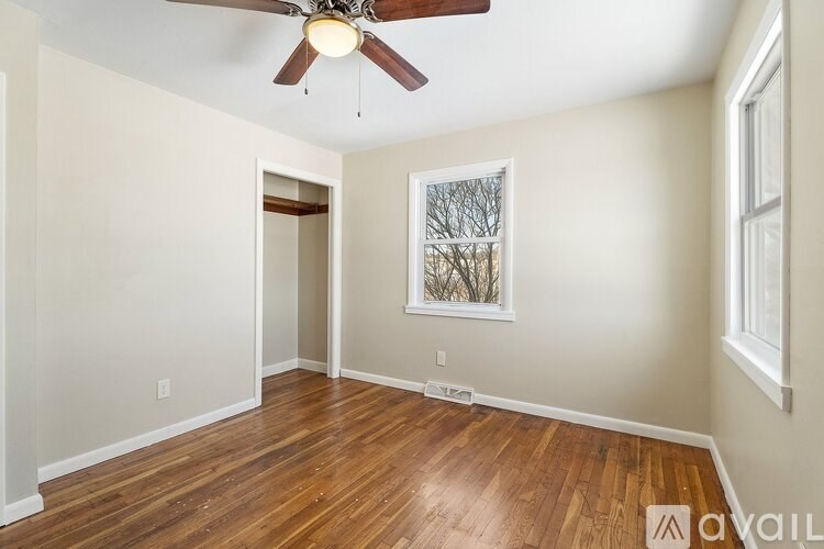 A room with a ceiling fan and wood flooring.