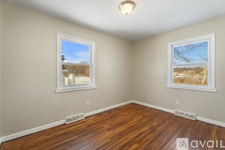 A room with wooden floors and two windows showing outdoor views.