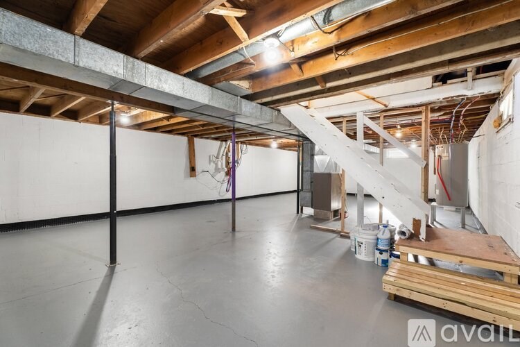 A large, empty room with a staircase under a wooden beam.