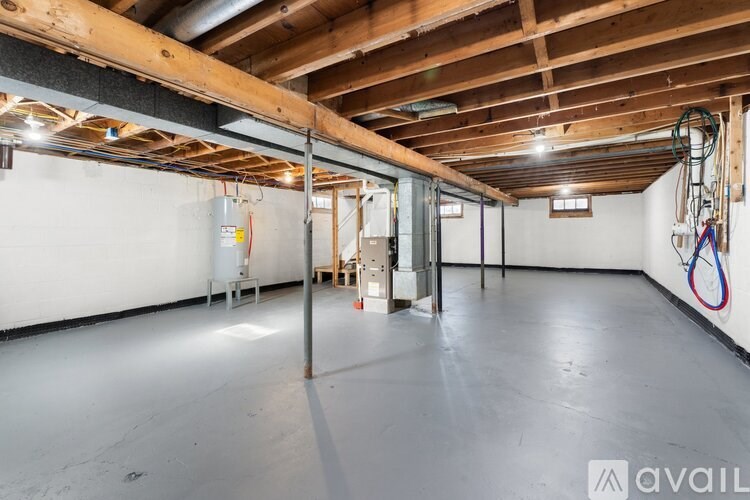 A spacious room with wooden beams on the ceiling and a white wall.