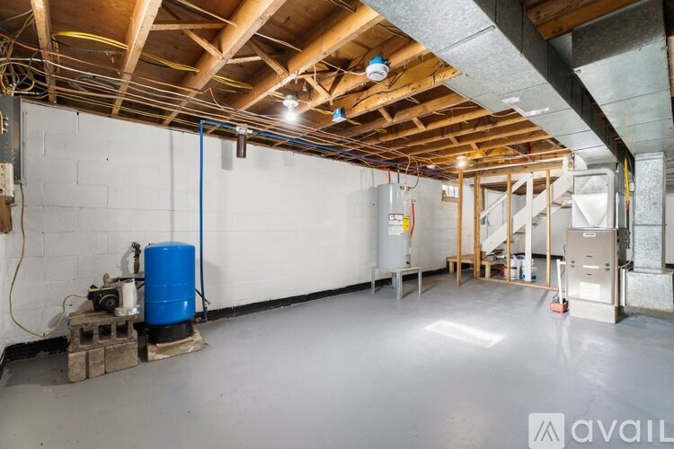 A spacious room with a blue water tank and wooden beams on the ceiling.
