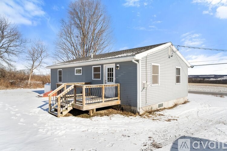 A small house with a porch is surrounded by snow.