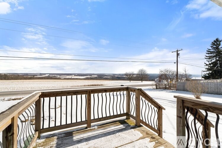 A wooden deck with a railing overlooking a snowy landscape.