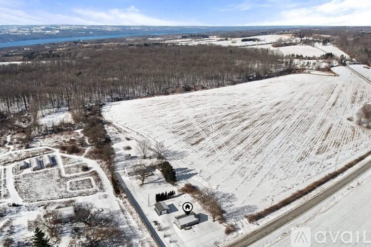 A winter landscape with a snow-covered field and a small building in the foreground.