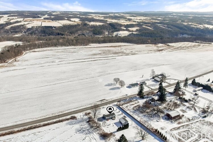 A snowy landscape with a road and a few buildings.