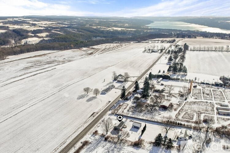 A snowy landscape with a large open field and a small building in the distance.