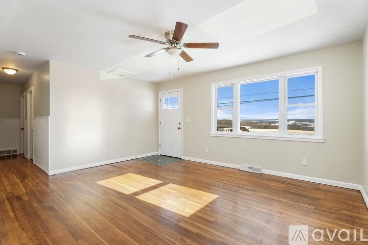 A room with a ceiling fan and wooden flooring.