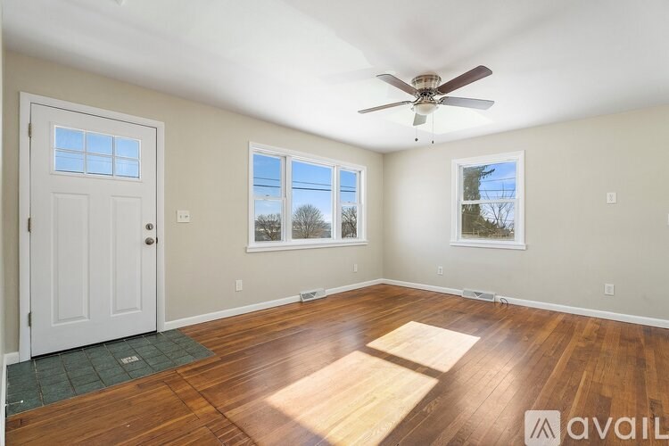 A room with a ceiling fan and two windows.