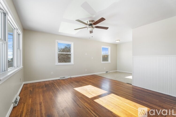 A spacious room with a ceiling fan and wooden flooring.