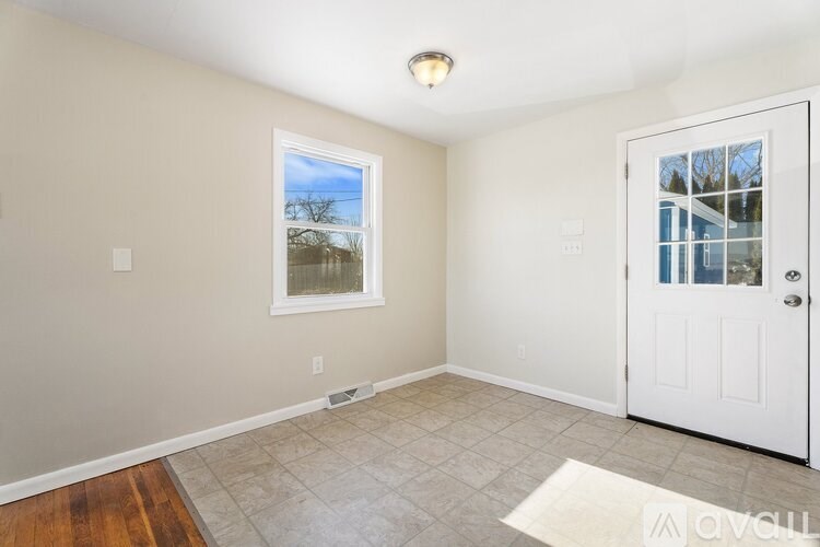 A room with a white door, a window, and a tiled floor.