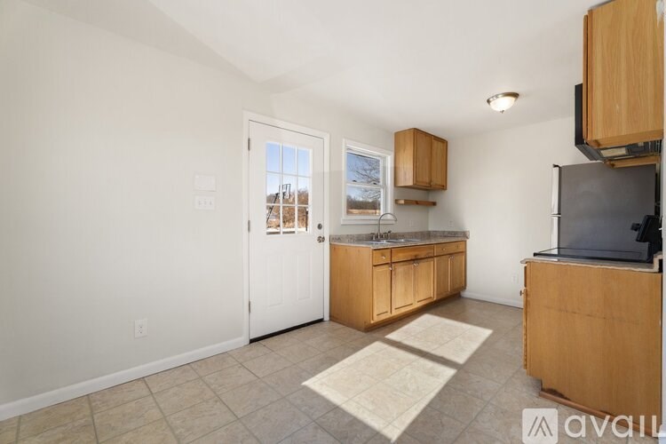A kitchen with wooden cabinets and a white door leading outside.