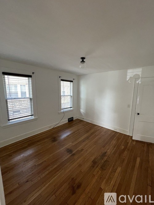 A room with wooden floors and two windows.