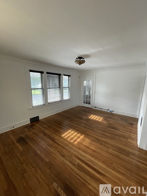 A room with wooden flooring and a window with blinds.