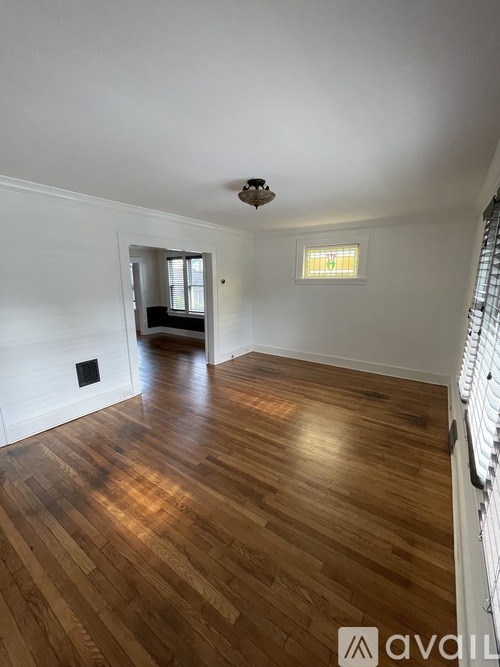 A room with wooden flooring and a window with blinds.