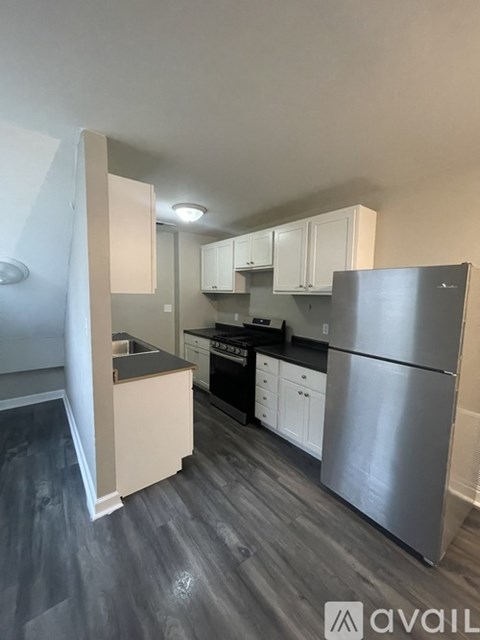 A kitchen with a refrigerator, stove, and cabinets.