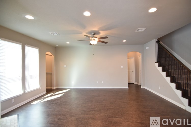 A spacious room with a staircase and a ceiling fan.