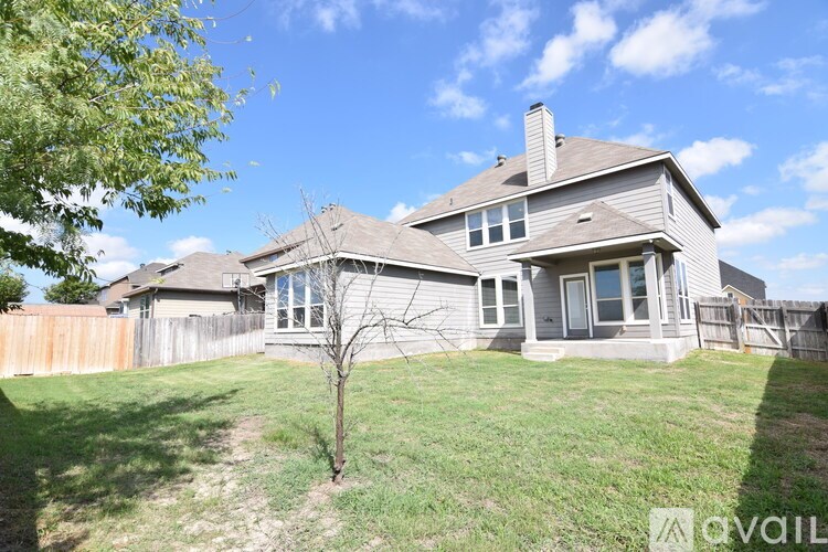 A house with a fence and a tree in front of it.