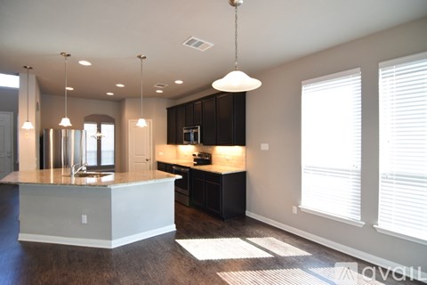 A modern kitchen with a center island and pendant lights.
