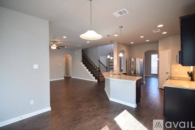 A spacious kitchen and living room with a staircase leading to the upper floor.