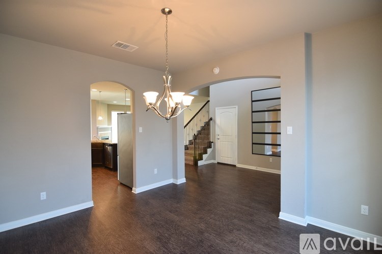 A large, empty room with a chandelier and a staircase.