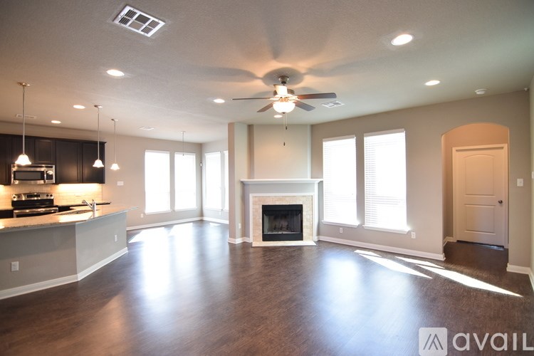 A spacious living room with a fireplace and a kitchen area in the background.