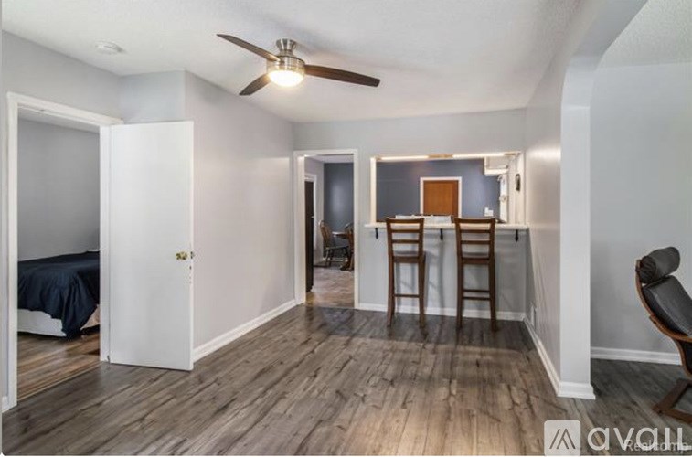 A room with a bed, a chair, and a ceiling fan.