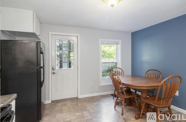 A kitchen with a black fridge and a table with chairs.