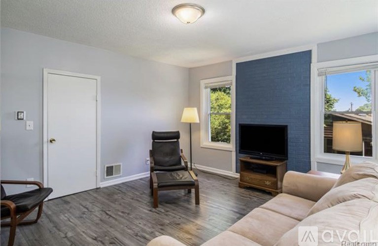 A living room with a couch, chair, and television.