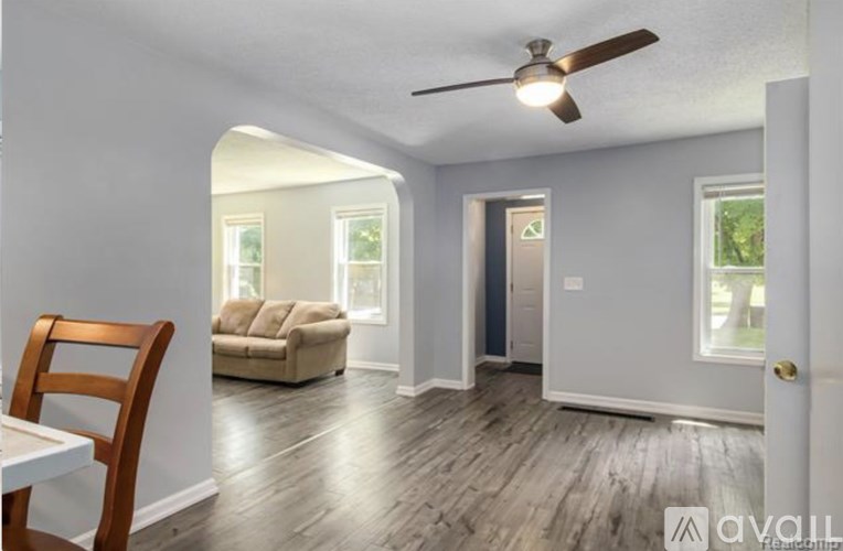 A room with a ceiling fan and a wooden chair.