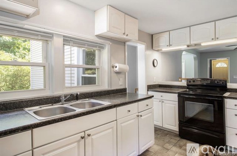 A kitchen with white cabinets and black countertops.