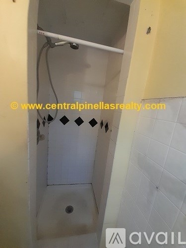 A shower stall with a white tile wall and a white shower head.