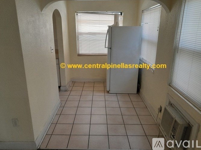 A room with a tiled floor and a white refrigerator.