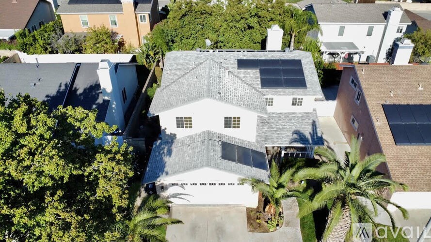A house with a white roof and a chimney is surrounded by trees.