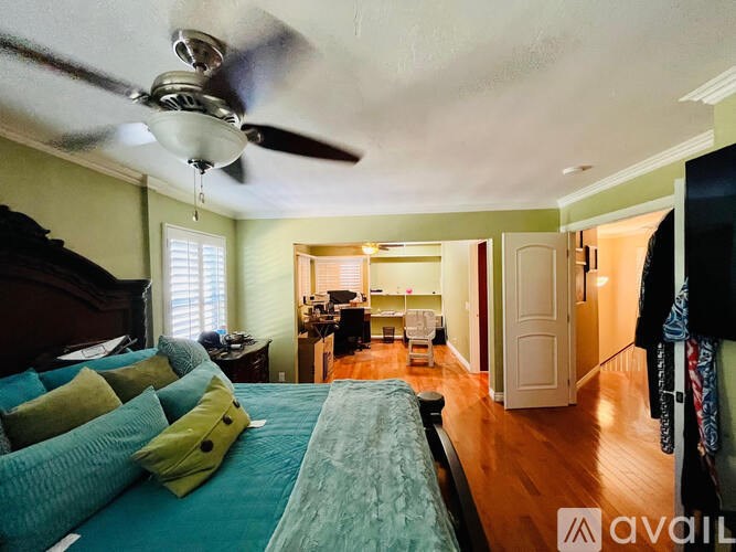 A bedroom with a bed, a ceiling fan, and a hallway.