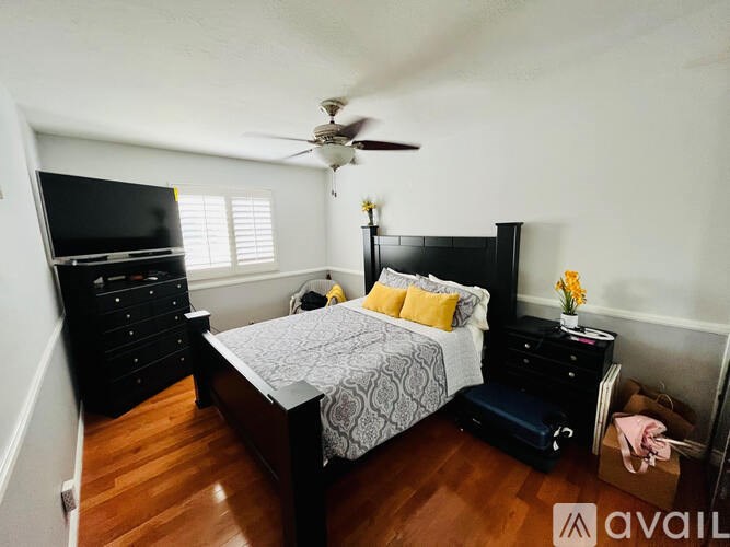 A bedroom with a bed, dresser, and ceiling fan.