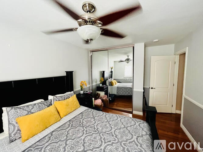 A bedroom with a bed, a ceiling fan, and a mirror.