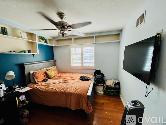 A bedroom with a bed, a ceiling fan, and a television.
