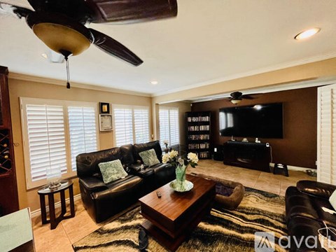 A living room with a black couch and a ceiling fan.
